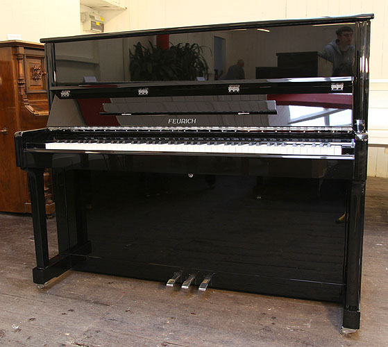 Brand new Feurich Model 122 upright piano with a black case and chrome fittings.  Piano has an eighty-eight note keyboard and three pedals.