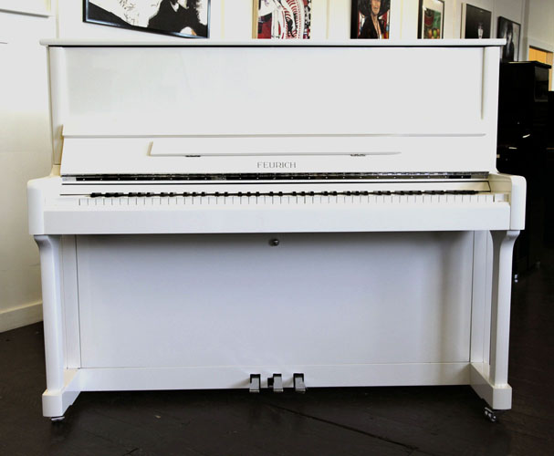 Brand New Feurich Model 122 upright piano with a white case and chrome fittings.  Piano has an eighty-eight note keyboard and three pedals.