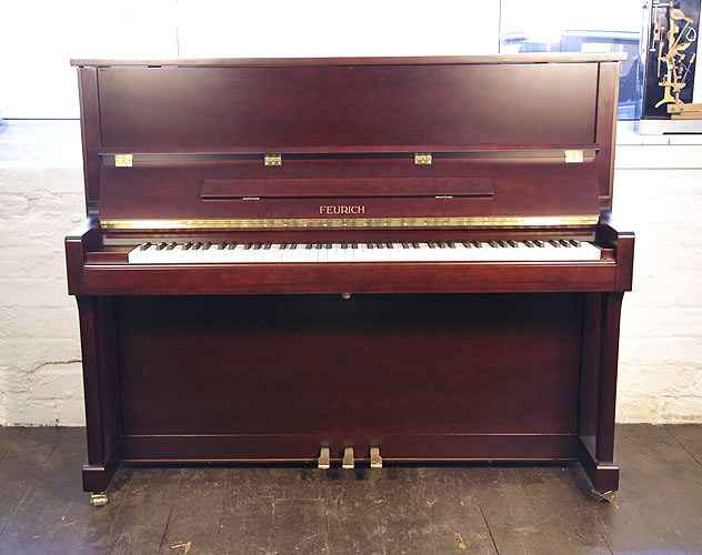 Brand New Feurich Model 122 upright piano with a satin, mahogany case and brass fittings. Piano has an eighty-eight note keyboard and three pedals.