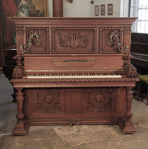 Antique, Georg Fortner upright piano for sale with a  mahogany case.  Entire cabinet is carved  in high relief.  The piano cheek feaures a carved grotesque head. The extravagant cabinet carvings were created by the famous wood sculpter, Julius Bechler, wood artist for King Ludwig II. Piano has an eighty-five keyboard and two pedals. 