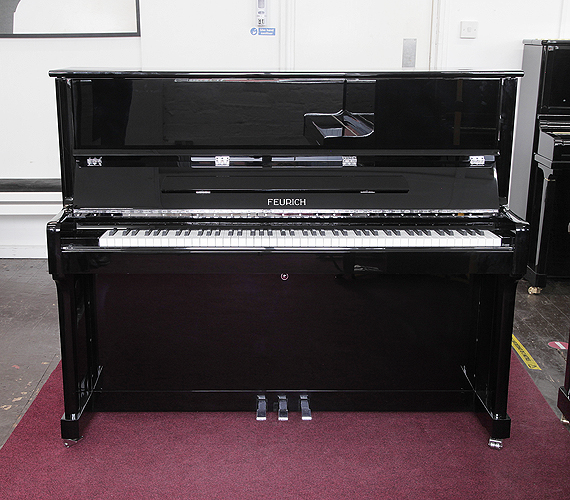 Brand new Feurich Model 122 upright piano with a black case and chrome fittings.  Piano has an eighty-eight note keyboard and three pedals.