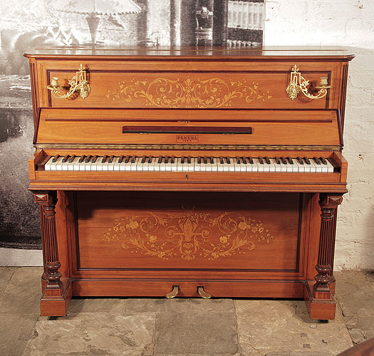 An 1893, Pleyel upright piano with a satinwood case, brass candlesticks and fluted, column legs. Entire cabinet features intricate, Neocalssical style inlay. Piano has an eighty-five note keyboard and two pedals
