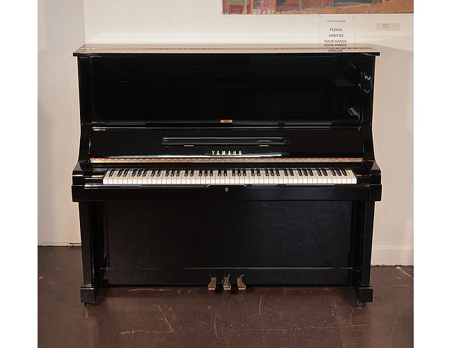 Reconditioned, 1979, Yamaha UX upright piano for sale with a black case and brass fittings. Piano has an eighty-eight note keyboard and three pedals. 