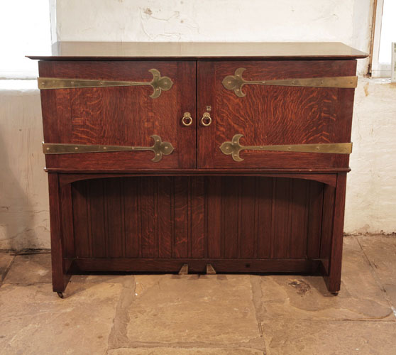 Arts and Crafts, 1904, Broadwood 'Manxman' piano with an oak case. Cabinet entirely encloses the instrument. Cabinet has studded brass strap hinges with Fleur-de-lis embellishment.  Designed by M. H. Baillie Scott.  Piano has an eighty-five note keyboard and two pedals.