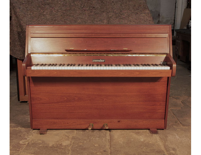 Pre-owned Zender upright piano with a polished, walnut case and brass fittings. Piano has an eighty-five note keyboard and two pedals. 