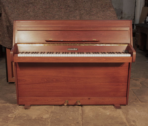Piano for sale. Pre-owned Zender upright piano with a polished, walnut case and brass fittings. Piano has an eighty-five note keyboard and two pedals. 