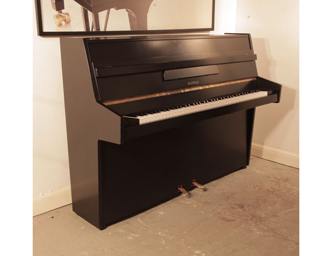 Reconditioned, 1970, Hupfeld  upright piano with a satin, black case and brass fittings. Piano has an eighty-five note keyboard and two pedals. 