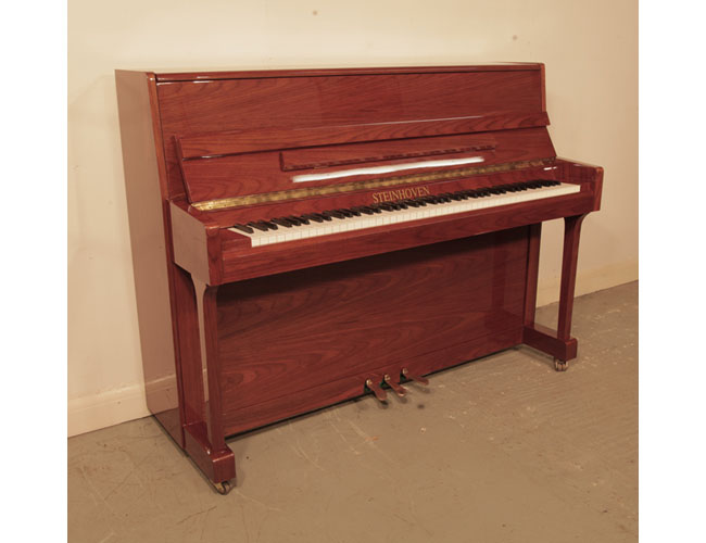 Reconditioned, 2000, Steinhoven  upright piano with a walnut case and polyester finish. Piano has an eighty-eight note keyboard and three pedals. 