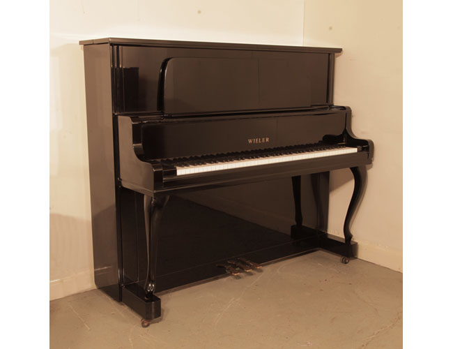 A 1980, Wieler U-5S upright piano with a black case, large music desk and cabriole legs. Piano has an eighty-eight note keyboard and three pedals. 