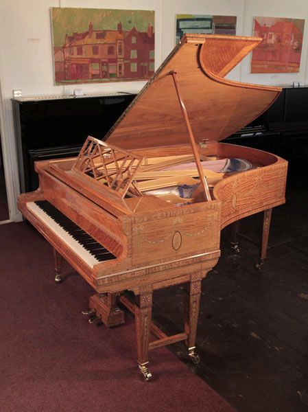 A 1911, Bluthner grand piano with a quarter cut satinwood case with boxwood stringing inlay. Entire cabinet inlaid with swagged bellflowers and bows. Piano has gate legs attached with a cross stretcher.  Piano has an eighty-eight note keyboard and a two-pedal lyre