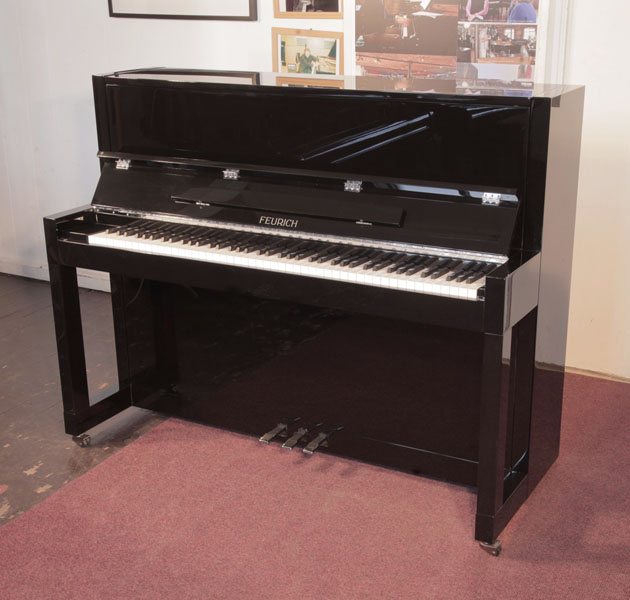 Reconditioned, 2013,  Feurich Model 115 Premiere upright piano with a black gloss case in Bauhaus style. Bauhaus style represented in the minimal, geometric cabinet styling. Piano has an eighty-eight note keyboard and three pedals. 