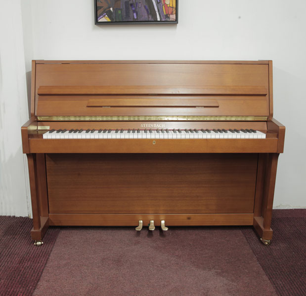 Steinbach UP108M upright piano with a walnut case. Piano has an eighty-eight note keyboard and three pedals.