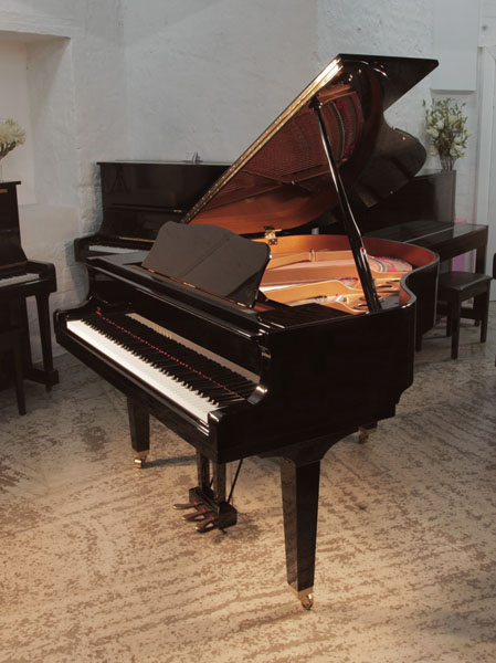 As new, 2022, Yamaha GB1 baby grand piano for sale with a black, gloss case and square, tapered legs.  Piano has an eighty-eight note keyboard and a three-pedal lyre. 